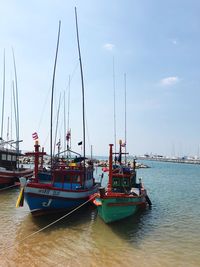 Boats moored at harbor against sky