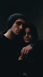 Young couple kissing against black background