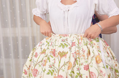 Close-up of woman holding umbrella standing against white wall