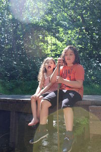 Siblings sitting on footbridge