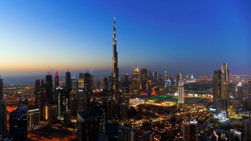 Illuminated cityscape against sky during sunset