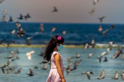 Side view of woman on beach against sky