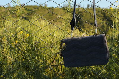 Close-up of a handbag against a field and a fence