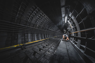 Full length of man crouching in tunnel