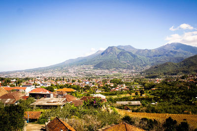 Scenic view of townscape by mountains against sky