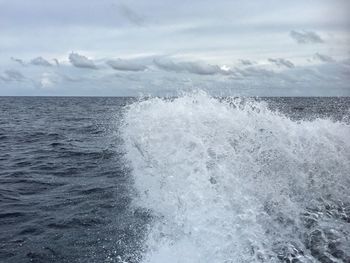 Waves splashing on sea against sky