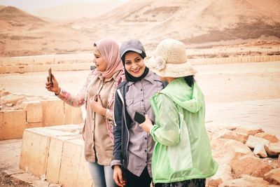 Woman wearing hat while standing on mobile phone