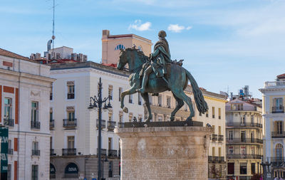 Low angle view of statue against buildings in city