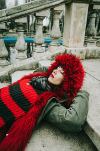 Woman with closed eyes in fur coat lying on staircase