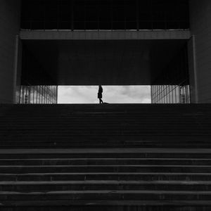 Silhouette man walking against building in city