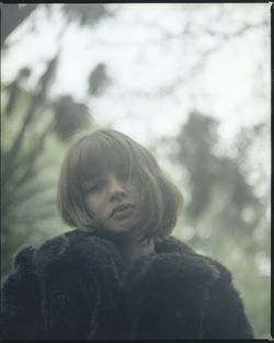 Portrait of girl looking at tree during winter