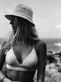 Woman in bikini wearing hat while standing against sea