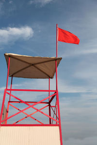 Red flag on beach against sky