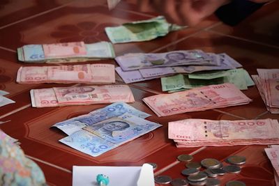 Cropped image of hand by currency on table