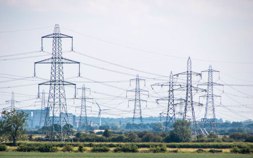 Low angle view of electricity pylon on field against sky