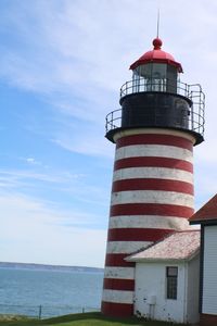 Low angle view of lighthouse by building against sky