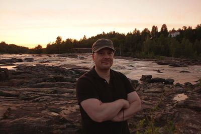 Portrait of young man standing against sky during sunset