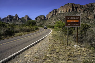 Road sign by mountains against sky