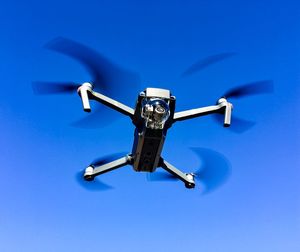 Low angle view of drone against clear blue sky