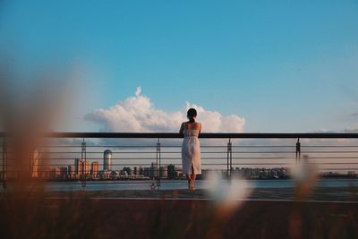 Rear view of young woman walking along the harbor 