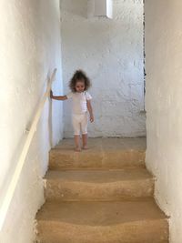 Girl walking on staircase against wall