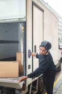 Female mover opening door of truck on street in city