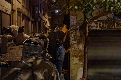 People on street amidst buildings in city at night