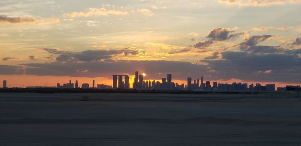 Scenic view of sea and buildings against sky during sunset