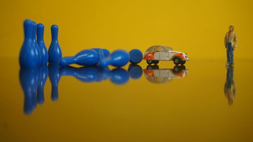 Close-up of figurine with toys against yellow background