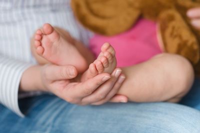 Midsection of woman touching feet of baby