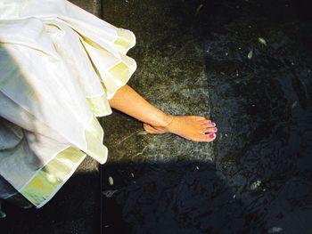 Low section of woman standing by water