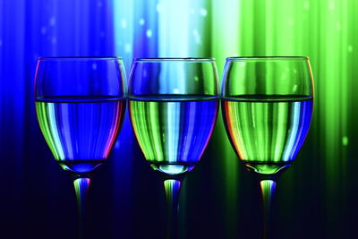 Close-up of wine in glasses against illuminated wall