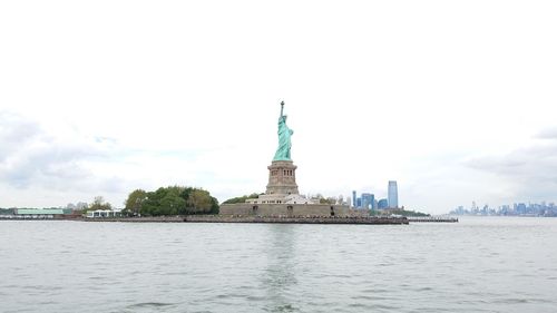 Statue of liberty by sea against sky in city