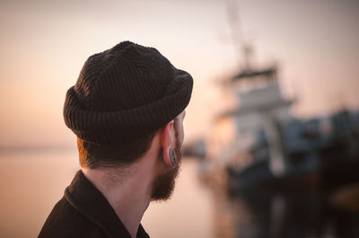 Close-up of man wearing knit hat against sky during sunset