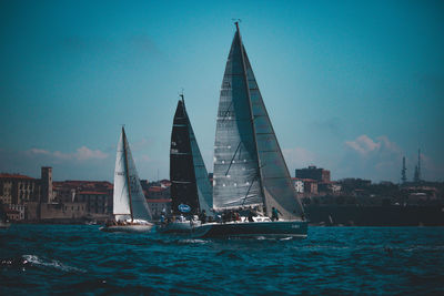 Sailboats sailing in sea against blue sky