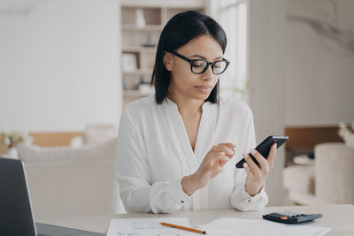 Young woman using mobile phone while sitting at home