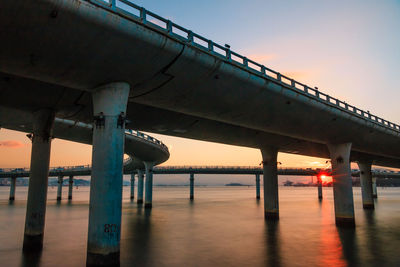 Low angle view of bridges over river at sunset