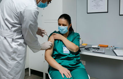 Midsection of doctor injecting patient in hospital