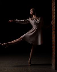 Full length of woman standing against black background