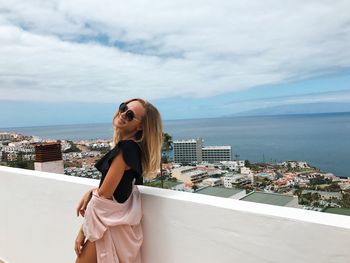 Side view of smiling woman standing on building terrace