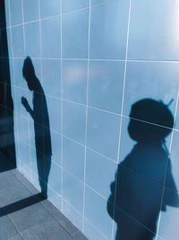 Shadow of man with arms raised in bathroom