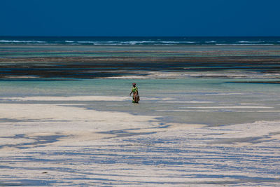 Woman at beach against clear sky