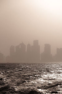 Sea by buildings in city against sky