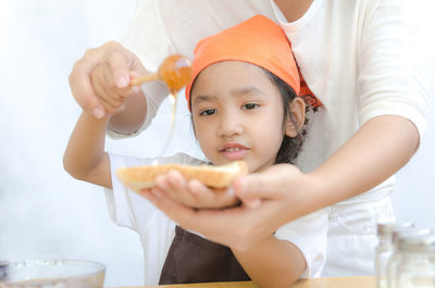 Midsection of woman with girl preparing food