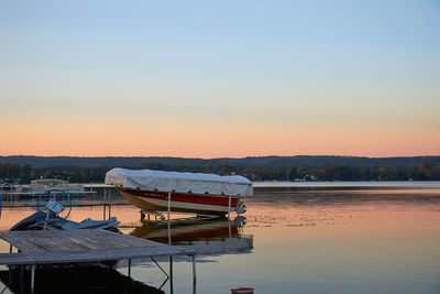 Boat moored in lake against sky during sunset