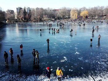 People swimming in frozen lake against sky