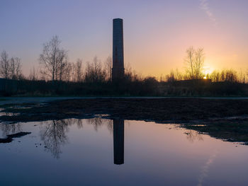 Reflection of tree in lake against sky during sunset