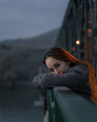 Portrait of woman leaning on railing of bridge