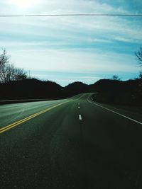 Road amidst green landscape against sky