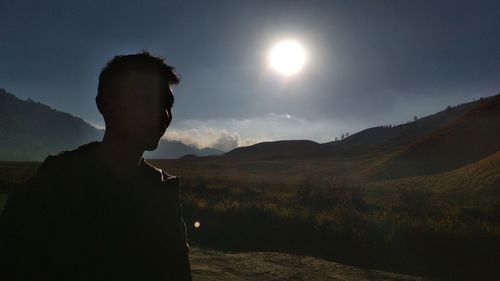 Silhouette man standing on field against sky at sunset